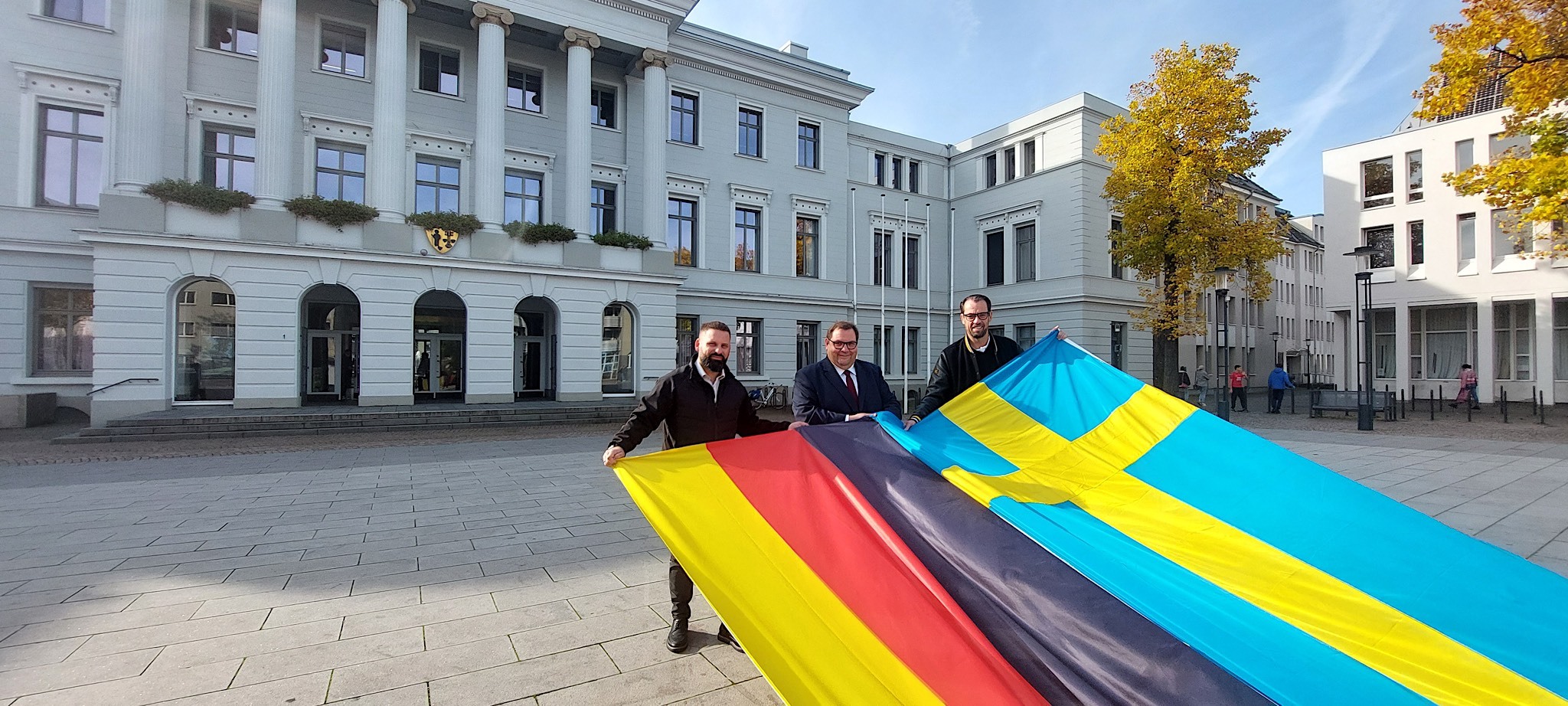 Zum Länderspiel der deutschen Nationalmannschaft im American Football gegen Schweden werden vor dem Krefelder Rathaus die schwedische und deutsche Flagge gehisst, im Bild (v. l.) Ravens-Vorstand Dino Volpe, Oberbürgermeister Frank Meyer und Ravens-Geschäftsführer Christoph Wittfeld. Foto: Stadt Krefeld, Presse und Kommunikation